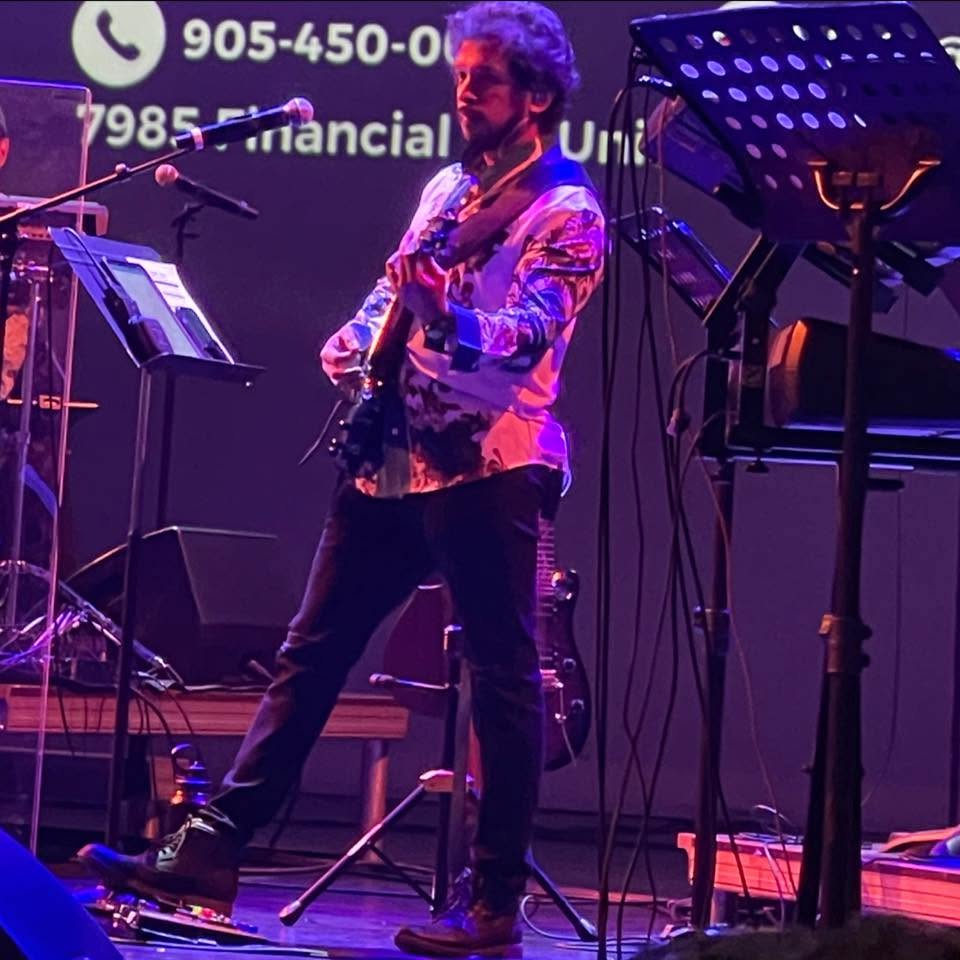 Glen Fernandez mid-solo under purple stage lighting