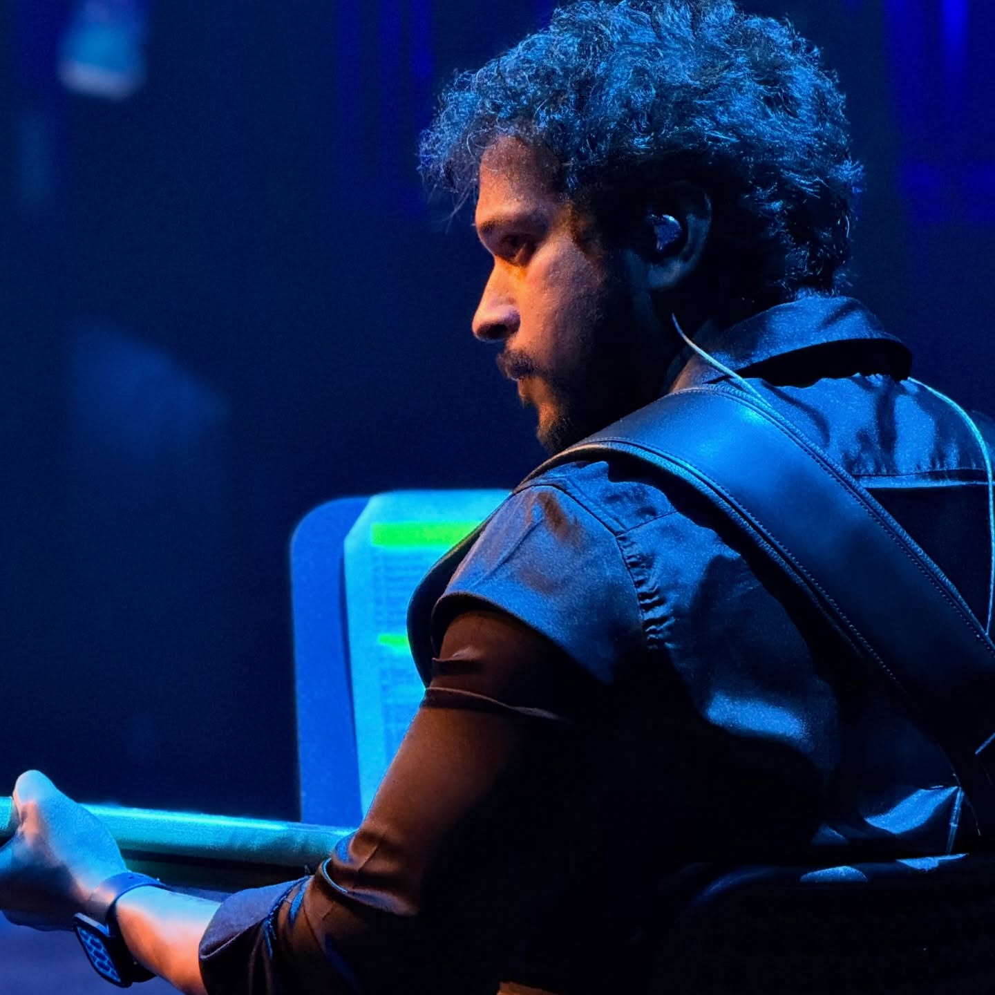 Glen Fernandez in profile on a blue-lit stage