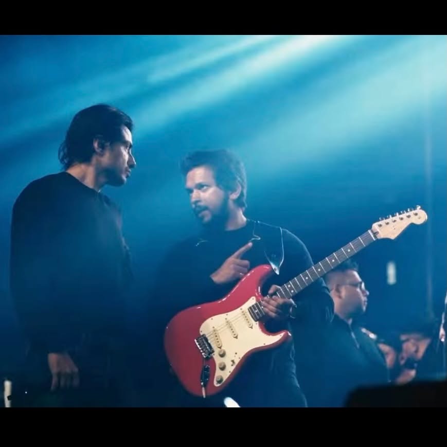 Glen Fernandez with a red Stratocaster in stage haze